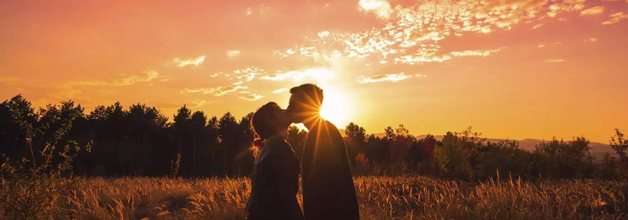 Couple kissing and holding hands in nature sundown